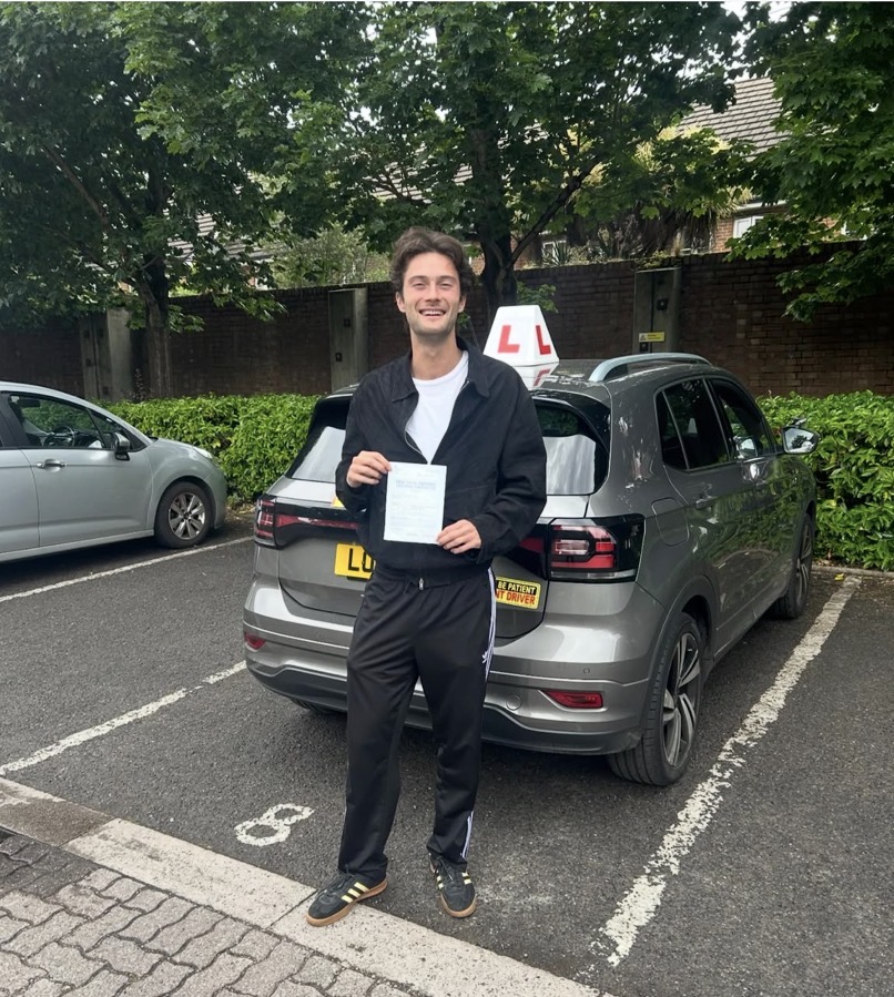 A GSM student smiling with their practical driving test pass certificate beside the GSM car